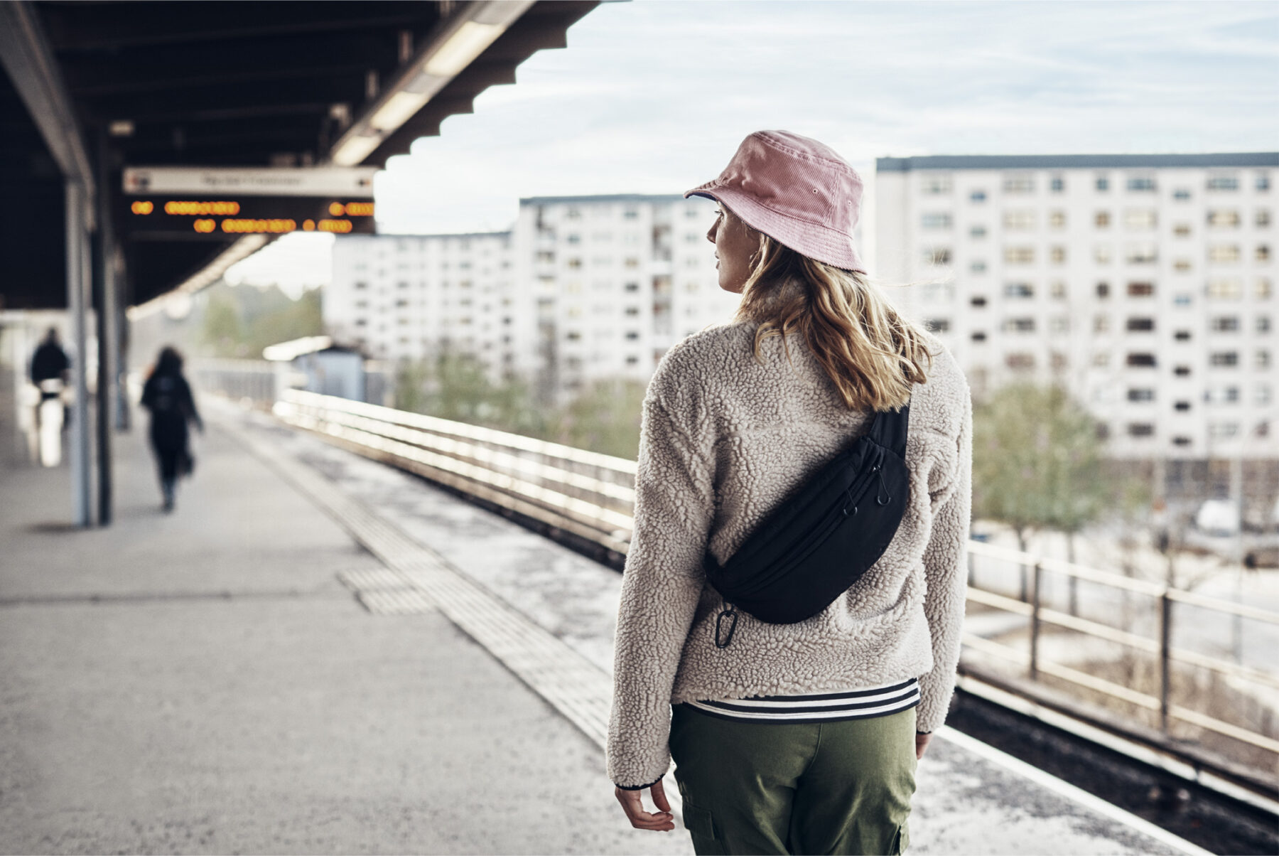 Ung kvinna står på en tunnelbaneperrong i en förort i Stockholm och väntar på tåget